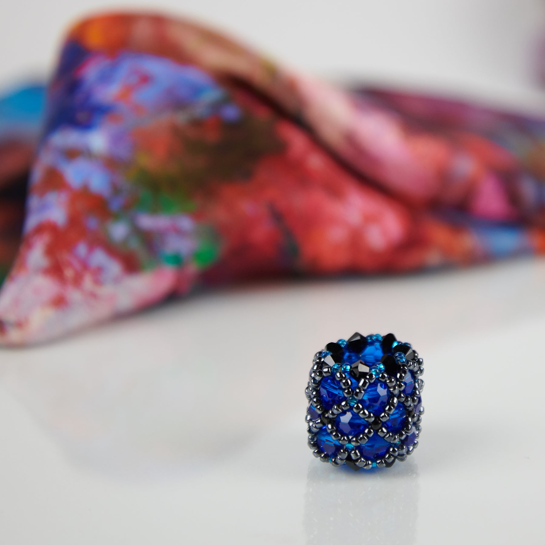 Close-up of blue handmade scarf ring, with a White Magnolias 100% silk Italian scarf in background.  Oksana_FineArtDesign