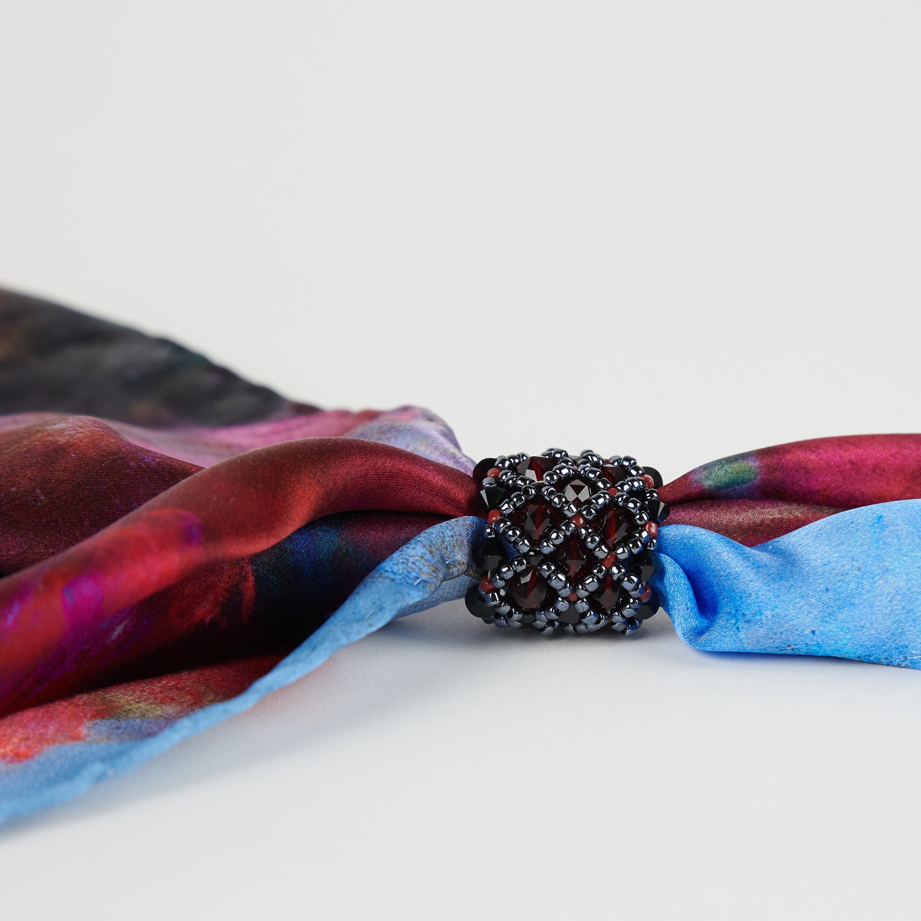 Close-up of dark red handmade scarf ring, with an Orange Bouquet 100% silk Italian scarf.