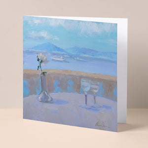 Floral fine art card based on original oil painting of flowers and glasses on a table, looking out over a bay with a volcano in background, partly open