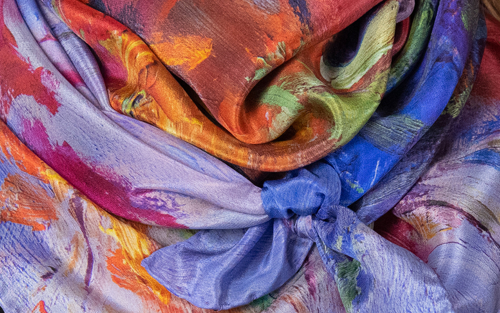 Close-up detail of multi-colored Lavender Dream Italian-made 100% silk scarf from Oksana Fine Art and Design, shown as tied around neck.