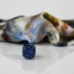 Close-up of blue handmade scarf ring, with a White Magnolias 100% silk Italian scarf in background.  Oksana_FineArtDesign