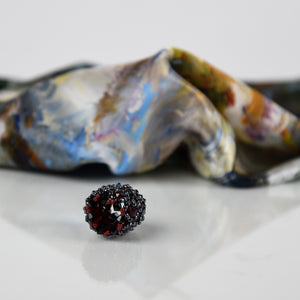 Close-up of dark red handmade scarf ring, with a White Magnolias 100% silk Italian scarf blurred in background.  Oksana_FineArtDesign